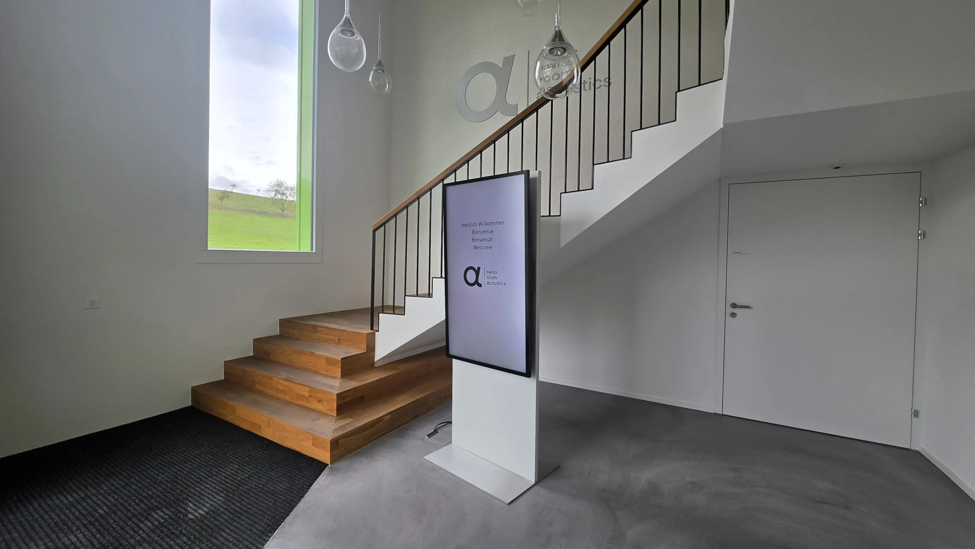 Flip-Stele im Empfang der Acsono AG mit Begrüssung in vier Sprachen neben der Treppe