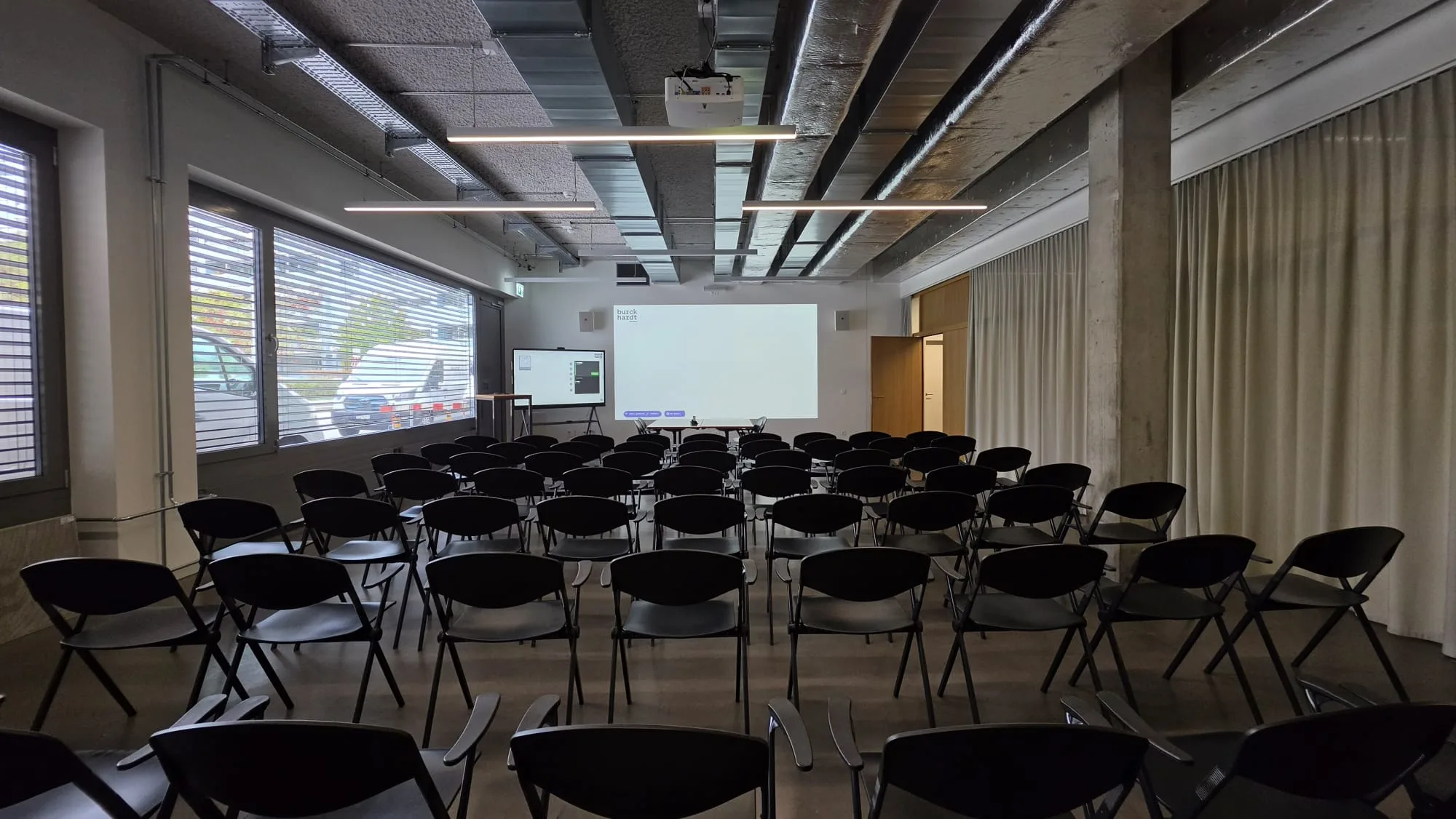 Saal der Burckhardt Architektur AG mit Leinwand und Bestuhlung