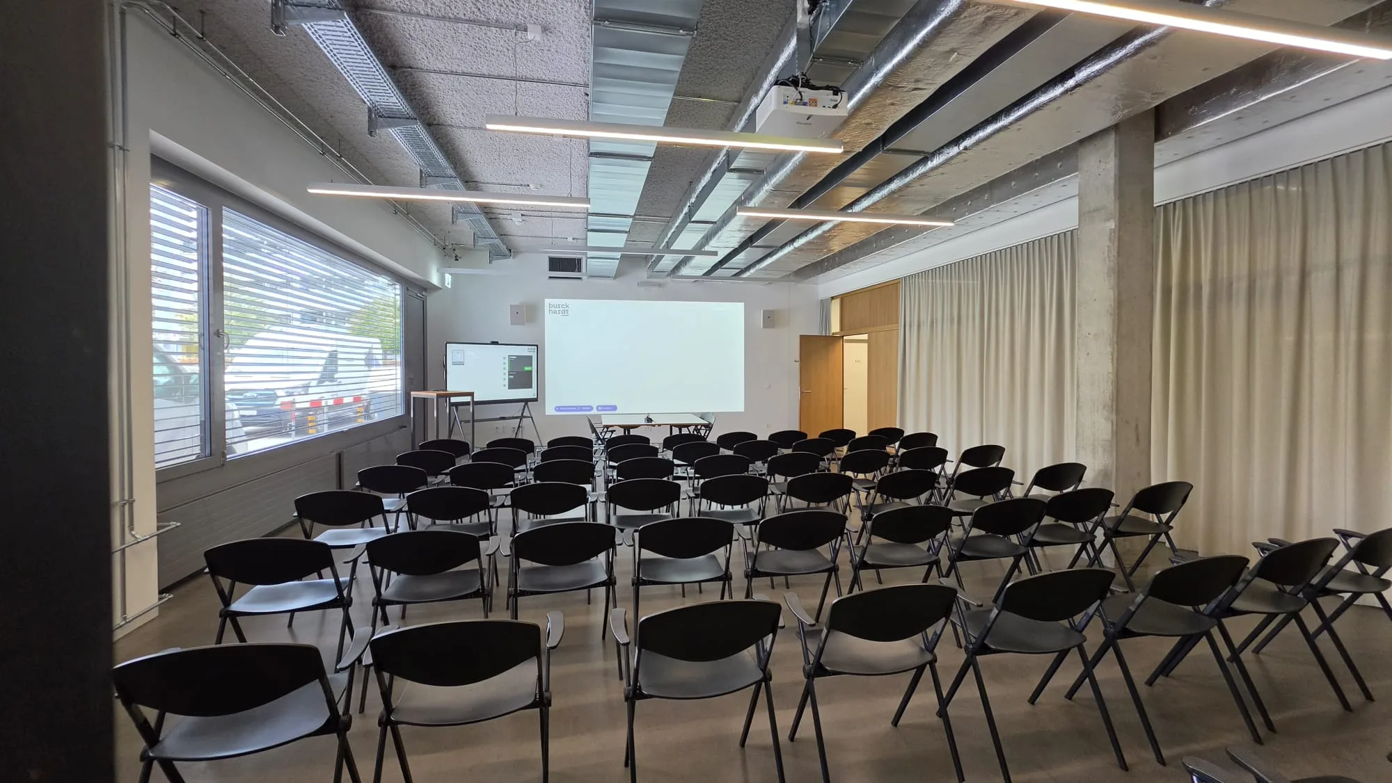 Bestuhlter Saal der Burckhardt Architektur AG mit Projektionsfläche