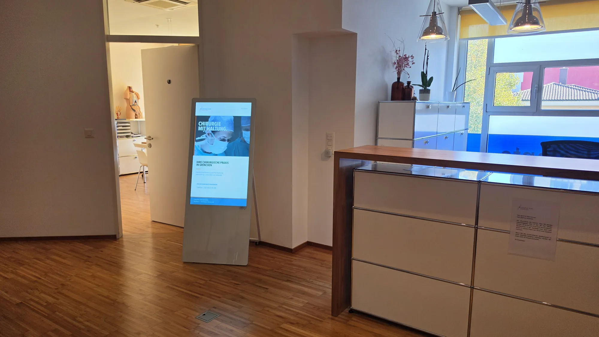 Kundenstopper im Hochformat neben dem Empfangstresen der Praxis in Grenchen