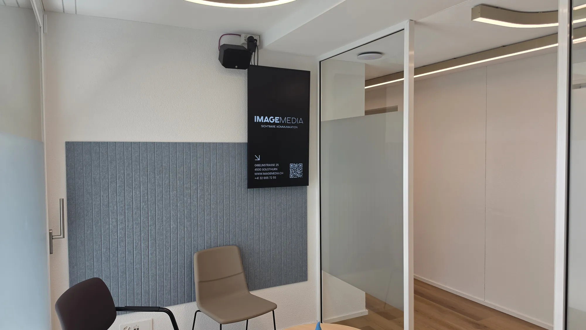 Dritter Digital-Signage-Screen im Wartebereich von SissaMed neben der Glaswand